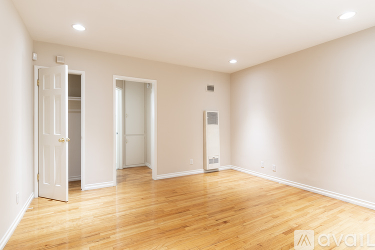 A room with wooden floors and white walls, with two doors and a window.