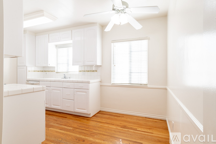 A kitchen with white cabinets and a wooden floor.
