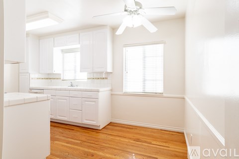 A kitchen with white cabinets and a wooden floor.