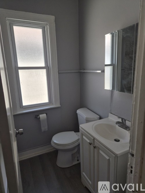 A bathroom with a toilet, sink, and window.