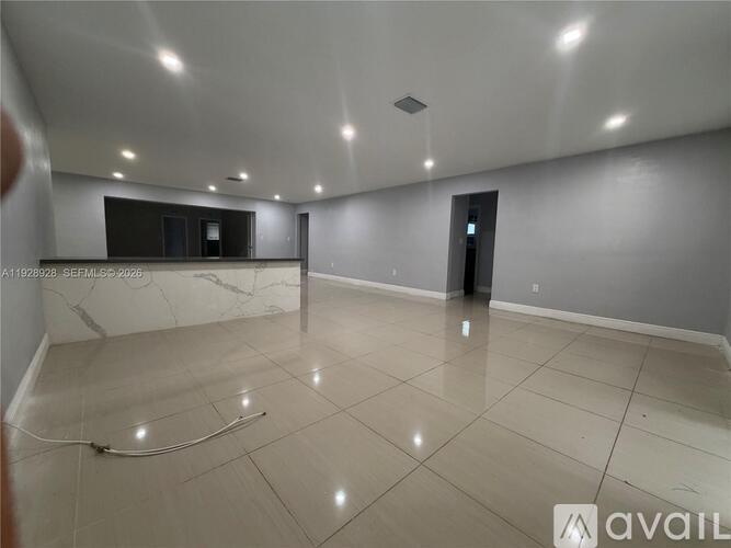 A spacious room with a marble floor and white walls.