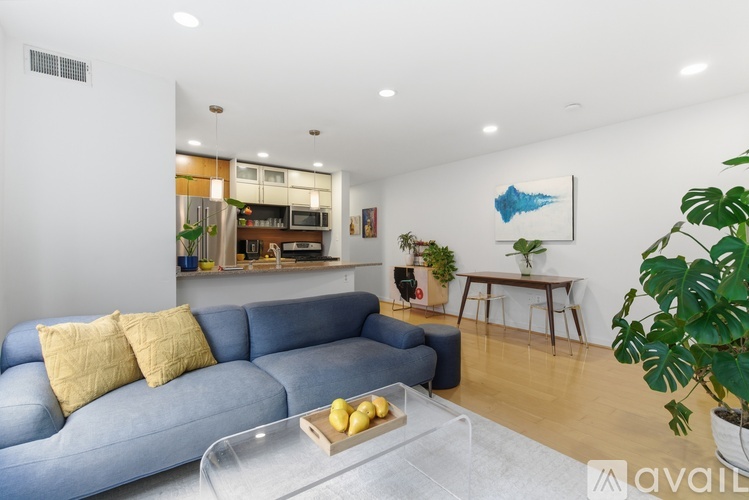 A living room with a blue couch and a glass coffee table.