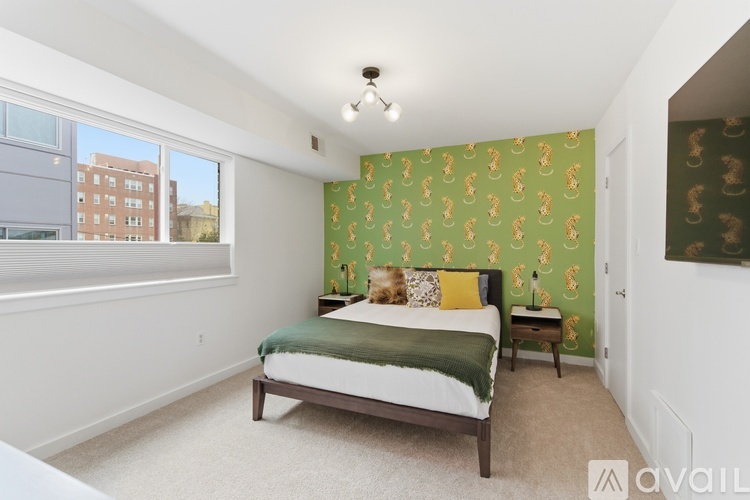 A bedroom with a bed, nightstand, and a wallpapered wall.