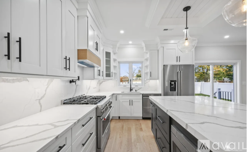 A modern kitchen with white cabinets and a marble countertop.