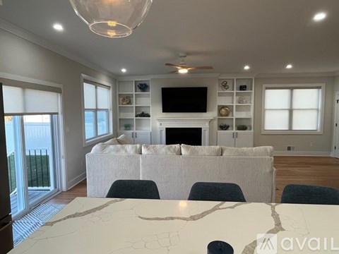 A living room with a white couch and a television on a shelf.