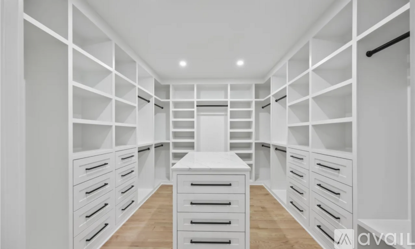A spacious walk-in closet with white shelving and drawers.