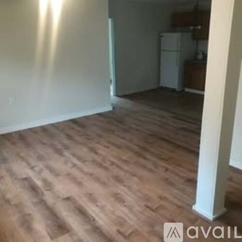A room with wooden flooring and a white refrigerator.