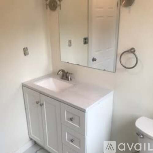 A white bathroom vanity with a mirror above it.