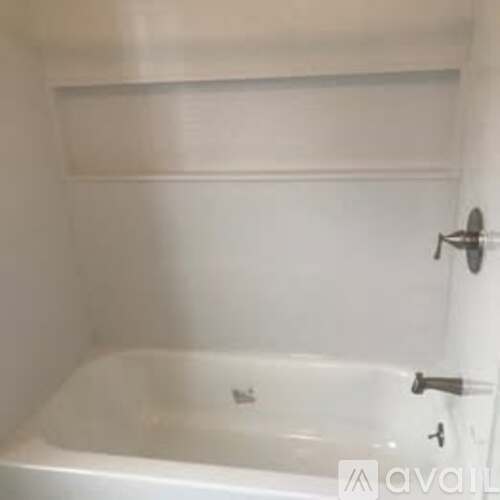A white bathtub with a shower head and faucet.