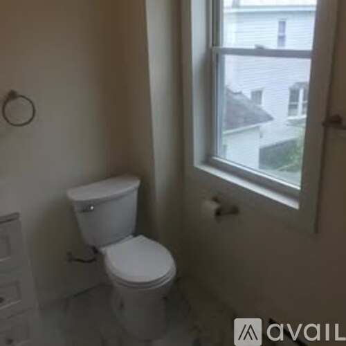 A white toilet in a bathroom with a window.