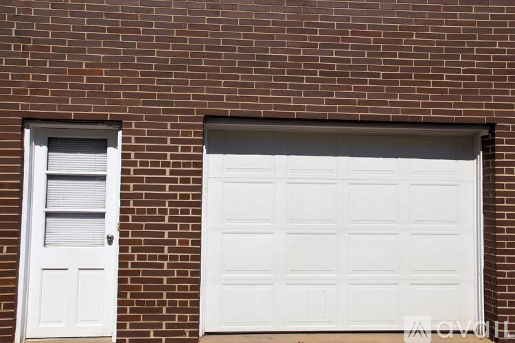 A white garage door is on the right and a white door with a window is on the left.