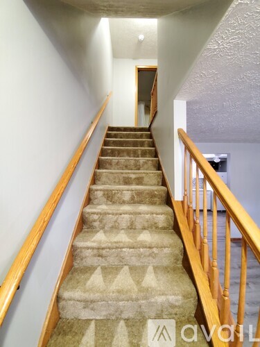 A staircase with a carpeted runner and wooden handrails.