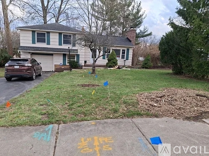 A house with a car parked in front and a tree with a blue flag on it.