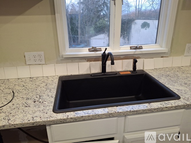 A black sink in a kitchen with a window above it.