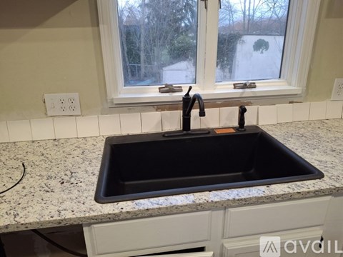 A black sink in a kitchen with a window above it.