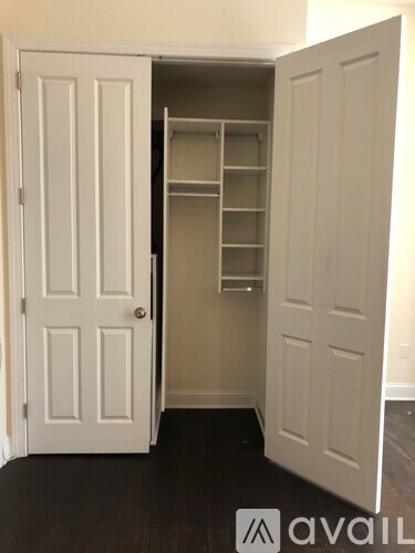 A white door is open to a small closet with shelves.