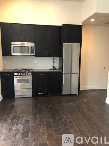 A kitchen with black cabinets and a stainless steel refrigerator.