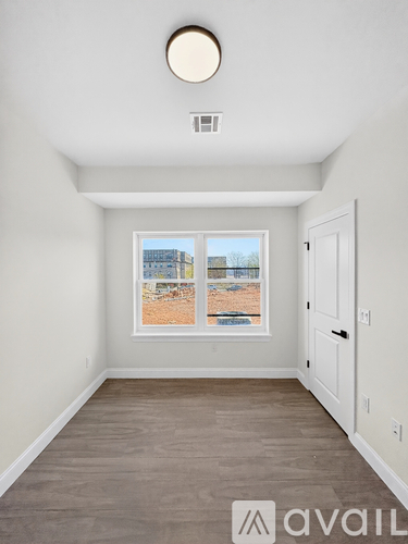 A room with a window showing a view of a building and a beach.