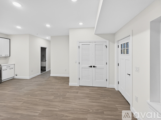 A spacious kitchen with white cabinets and a wooden floor.