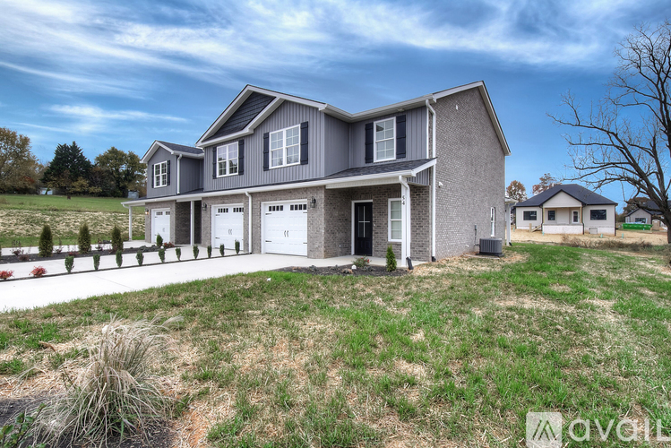 A modern house with a grey exterior and a large front yard.