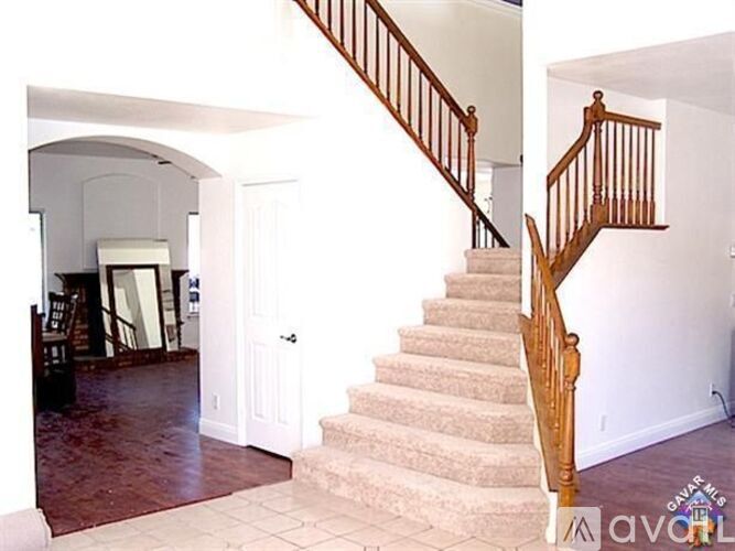 A staircase with a wooden banister and beige carpeted steps.