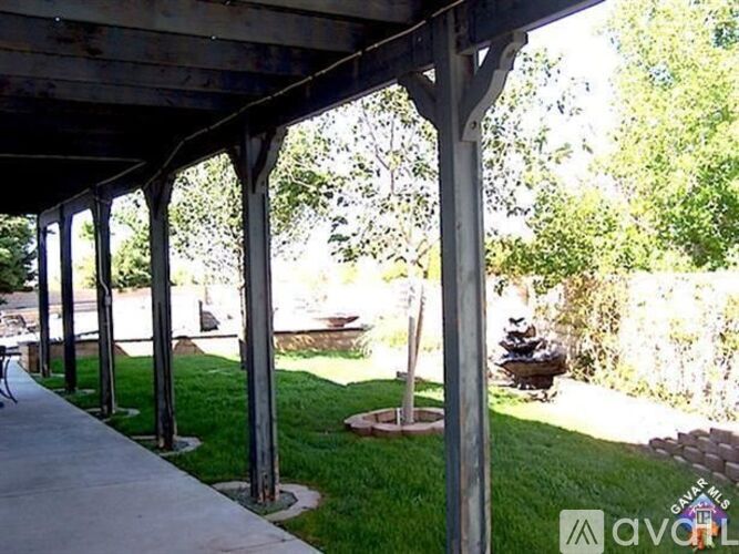 A patio with a white pergola and a concrete walkway.