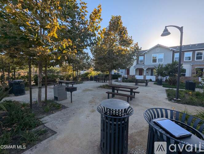 A park with benches, trees, and a building in the background.