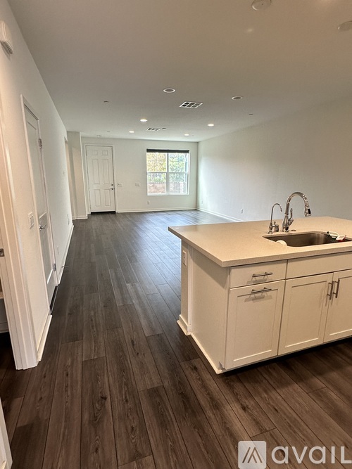 A kitchen with white cabinets and a wooden floor.