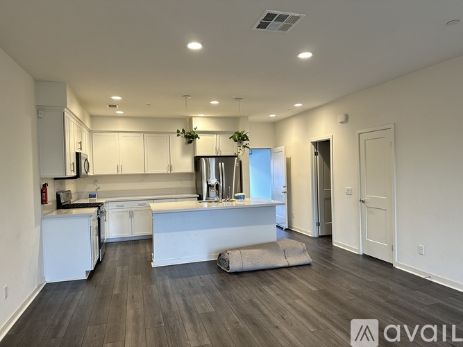 A modern kitchen with white cabinets and a wooden floor.