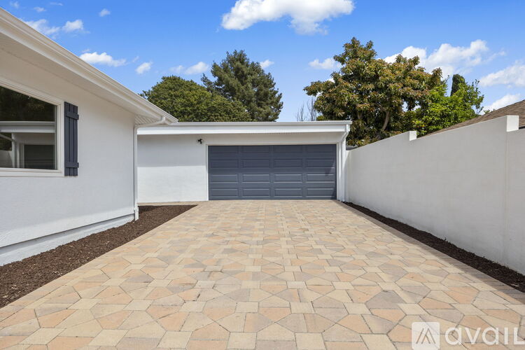 A white house with a tiled driveway and a closed grey garage door.