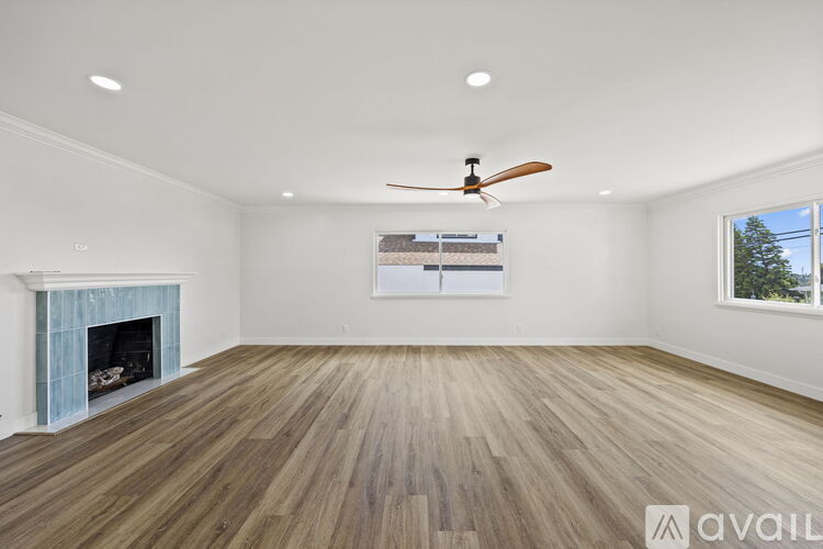 A spacious room with a fireplace and a fan on the ceiling.