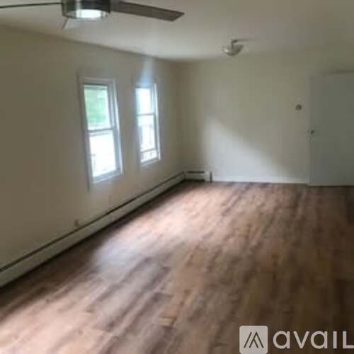 A room with wooden flooring and two windows.