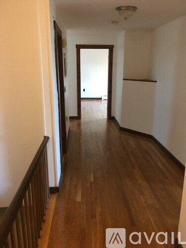 A hallway with wooden floors and a white wall.