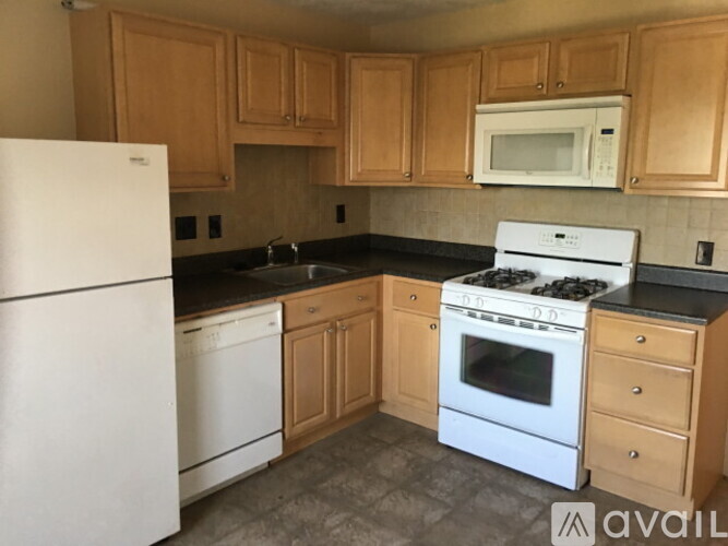 A kitchen with white appliances and wooden cabinets.