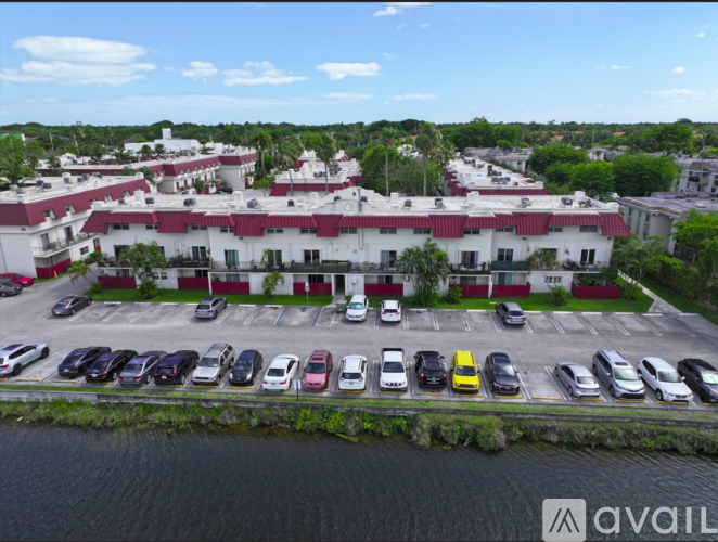 A parking lot with cars parked in front of a building with a red roof.