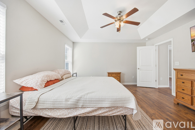 A bedroom with a bed, dresser, and ceiling fan.