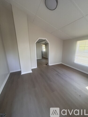 A room with wooden flooring and white walls, with a circular object on the ceiling.
