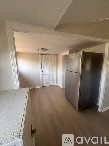 A kitchen with a refrigerator, cabinets, and a doorway leading to another room.