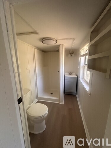 A small bathroom with a toilet, a washing machine, and a shower.