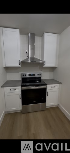 A kitchen with white cabinets and a stainless steel range hood.