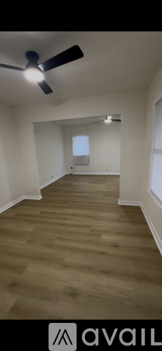 A room with a ceiling fan and wooden flooring.