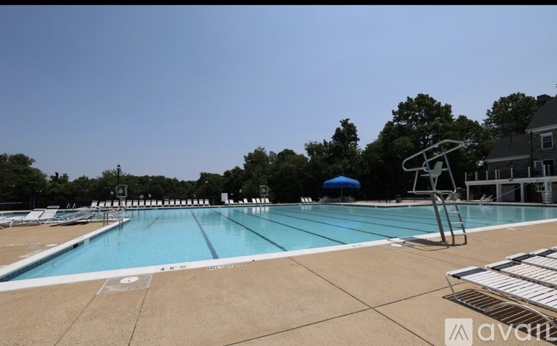 A large outdoor swimming pool with a diving board and a blue umbrella.