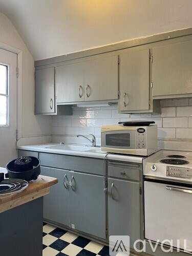 A kitchen with a white sink and a white and black checkered floor.