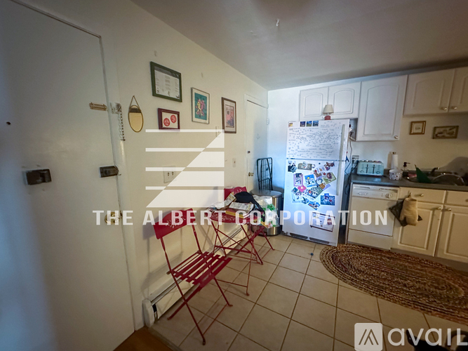 A kitchen with white cabinets and a fridge filled with magnets and papers.