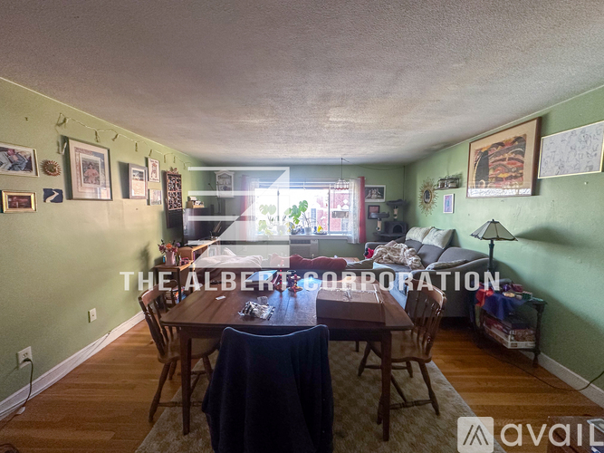 A dining room with a table set for four and a couch with a blanket on it.