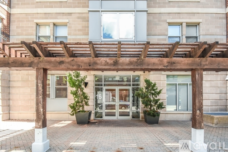 A building entrance with a wooden pergola and potted plants.