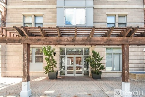 A building entrance with a wooden pergola and potted plants.