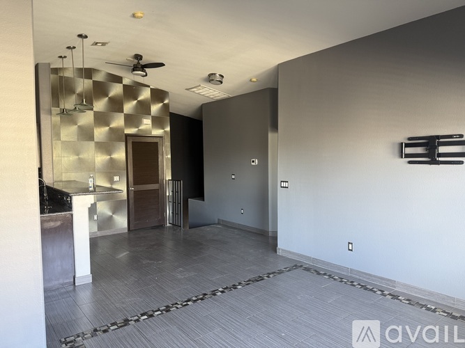 A room with a checkered tile wall and a ceiling fan.