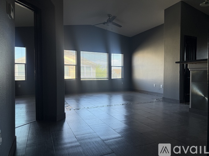 A spacious room with a ceiling fan and large windows.