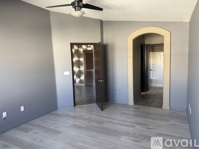 A room with a ceiling fan and a doorway leading to another room.